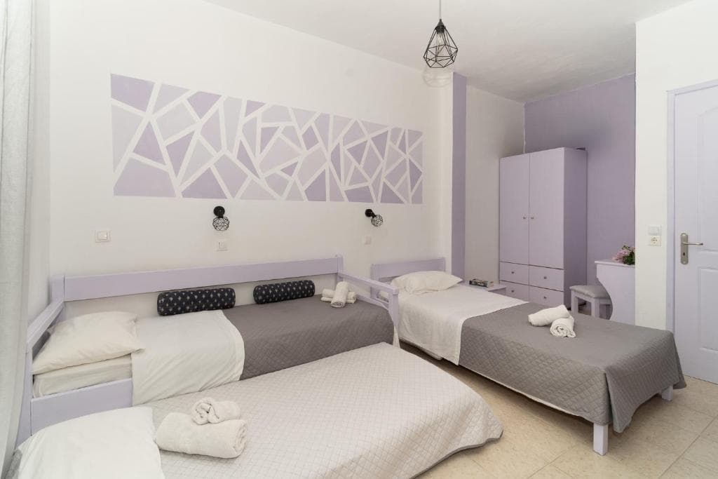 A triple room with single beds and a geometric pattern on the wall in a Blue Houses maisonette